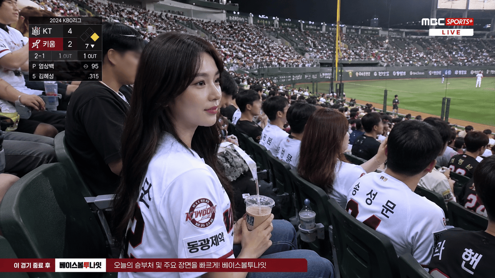 KBO stadium broadcast fan cam with crowd, field, and TV texture